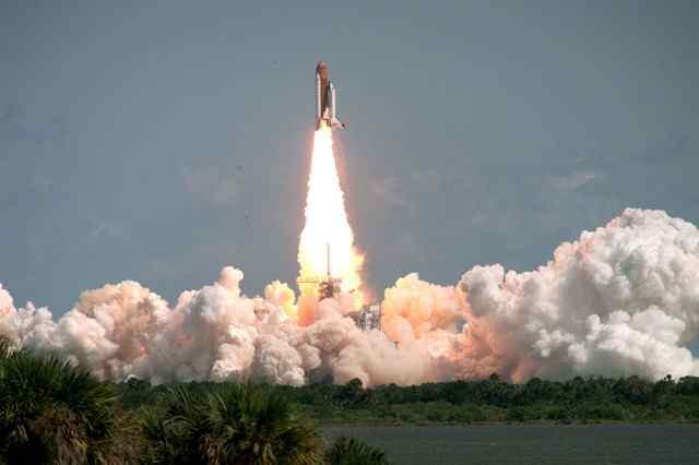 Space Shuttle Columbia rising from the launch pad on a column of flame and smoke