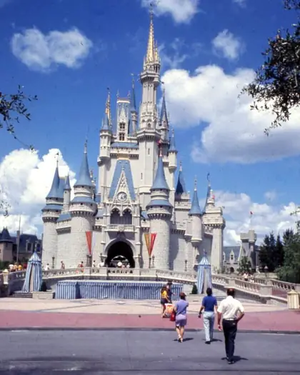 Cinderella Castle at Magic Kingdom in 1974, with blue-roofed spires and visitors walking toward it