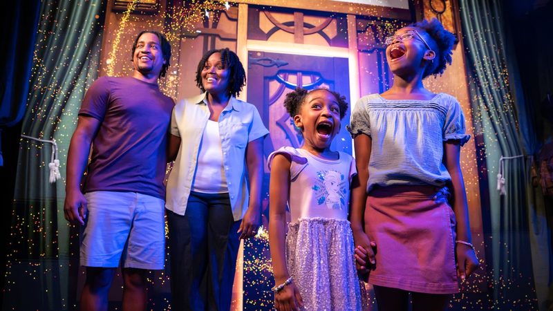 A family laughing on a Frozen-themed set at the Disney PhotoPass Studio