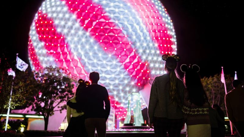 Spaceship Earth lit in red and white holiday lights