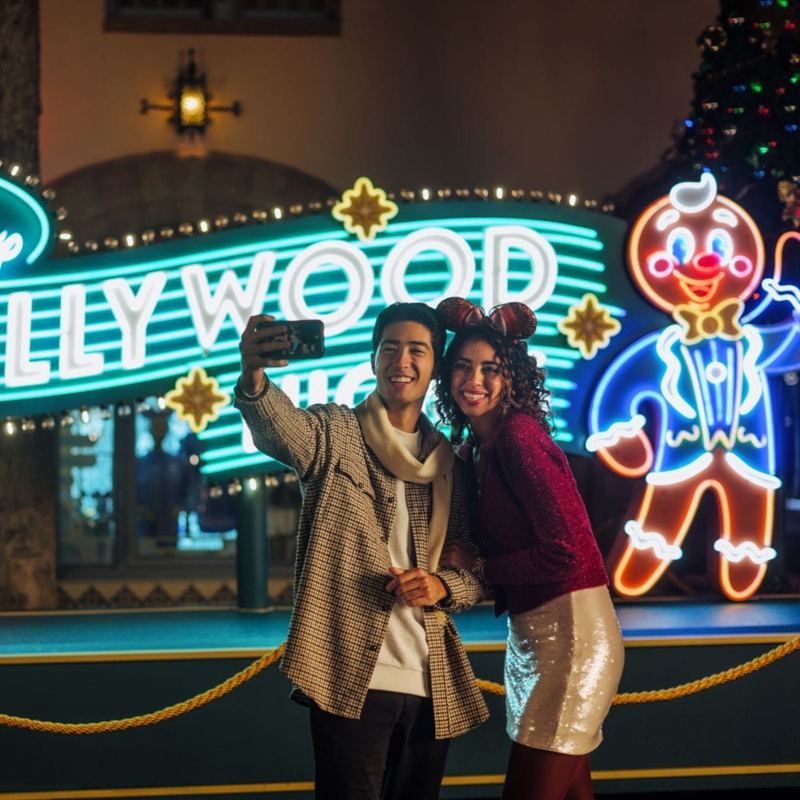Guests taking a selfie in front of a Jollywood neon sign